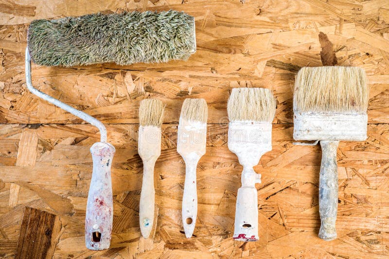 Old used brushes on OSB surface. Old used brushes and painting roller on OSB background stock images